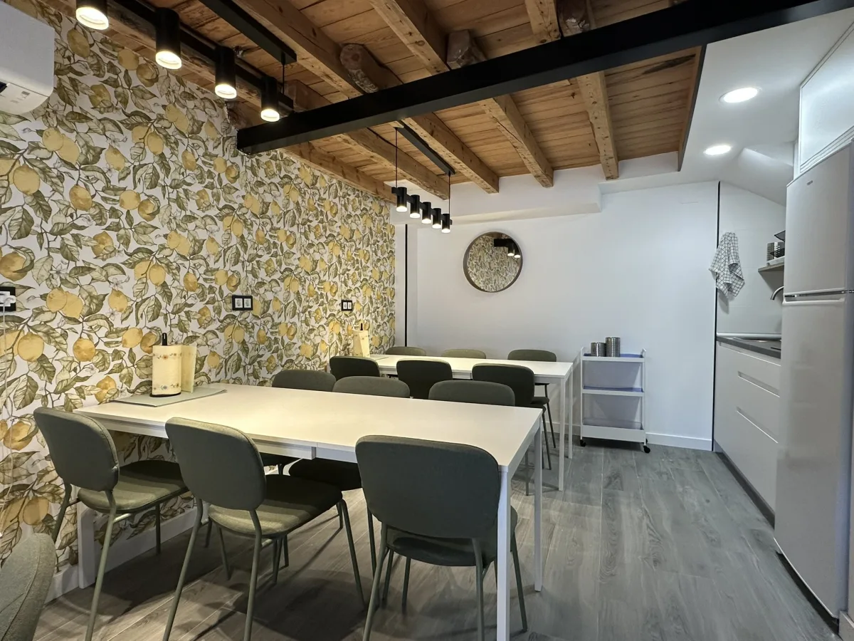 Comedor del albergue con techo de vigas de madera y papel pintado de flores