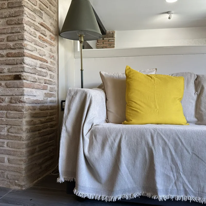 Rincón del salón con sofá junto a la pared de ladrillo