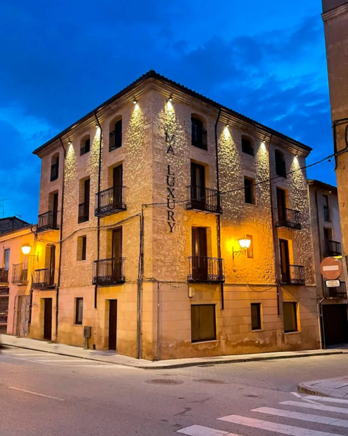 Edificio de piedra de los Apartamentos Uxama Luxury Epona iluminado al anochecer