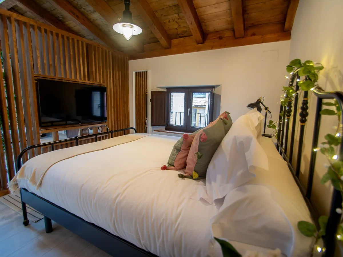 Dormitorio del ático KARA con cama de matrimonio y vigas de madera