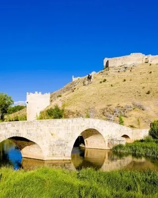 Puente medieval sobre el río y ruinas del castillo de Osma en lo alto